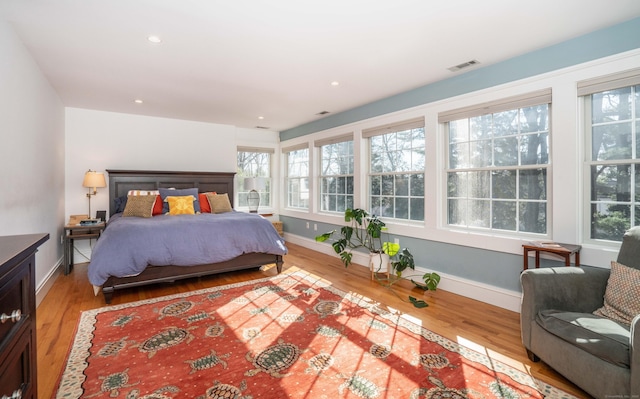 bedroom with visible vents, multiple windows, and wood finished floors