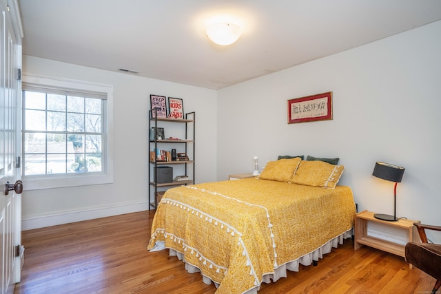 bedroom with visible vents, baseboards, and wood finished floors