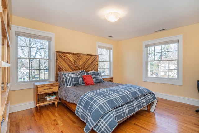 bedroom with visible vents, baseboards, and wood finished floors