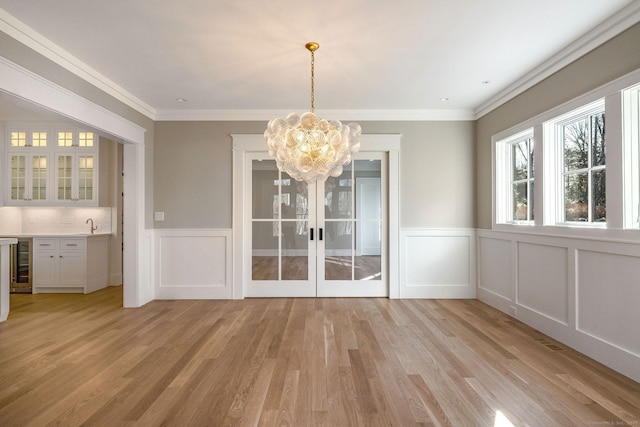 412 Tanner Marsh Rd, Guilford, CT 06437 - unfurnished dining area with light wood-style flooring, a chandelier, a decorative wall, wainscoting, and wine cooler