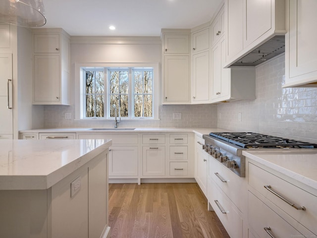412 Tanner Marsh Rd, Guilford, CT 06437 - kitchen with a sink, stainless steel gas stovetop, light wood-style flooring, tasteful backsplash, and white cabinetry