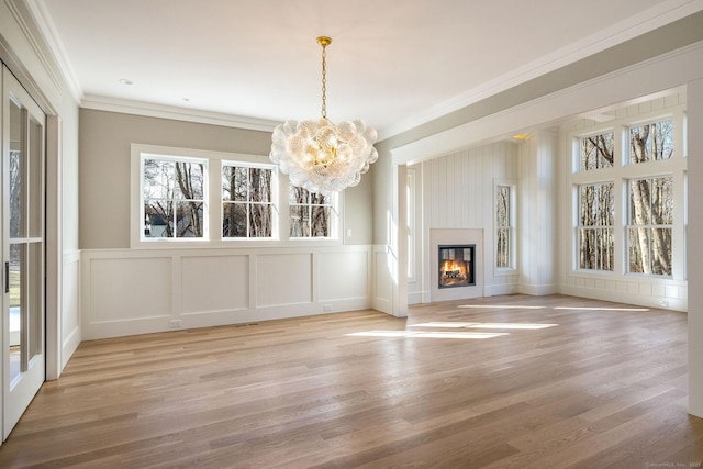 412 Tanner Marsh Rd, Guilford, CT 06437 - unfurnished living room with a chandelier, a decorative wall, ornamental molding, wood finished floors, and a wainscoted wall