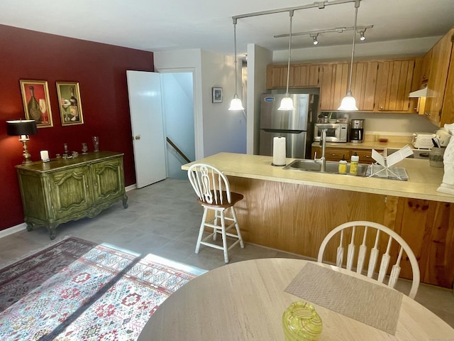 kitchen featuring a sink, freestanding refrigerator, a peninsula, light countertops, and white microwave