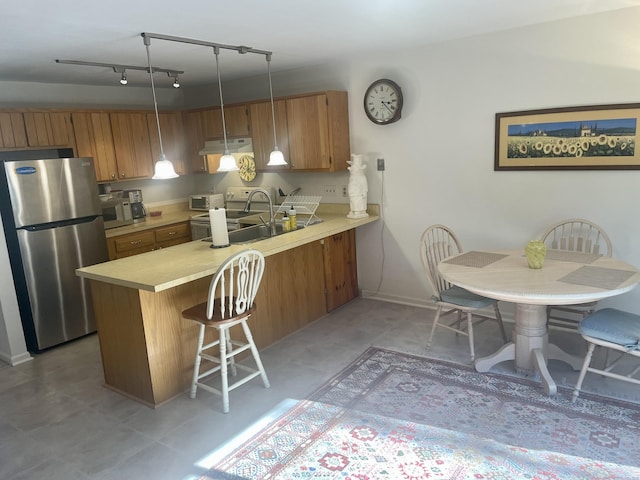 kitchen featuring light countertops, brown cabinets, appliances with stainless steel finishes, and a sink