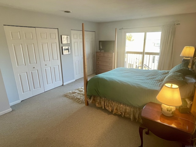 carpeted bedroom featuring baseboards and two closets