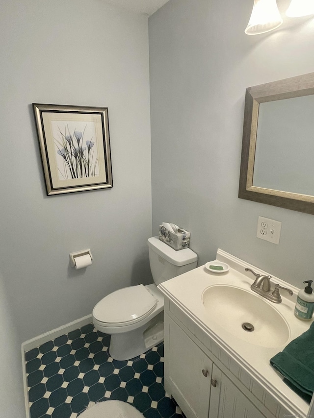 half bathroom with baseboards, toilet, and vanity