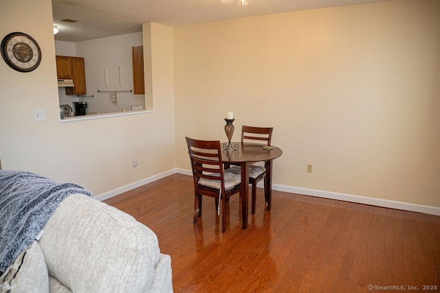 dining area featuring baseboards, a textured ceiling, and wood finished floors