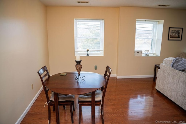 dining room featuring a wealth of natural light, visible vents, baseboards, and wood finished floors