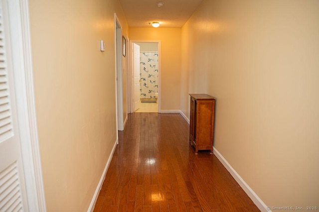 hallway featuring dark wood-type flooring and baseboards