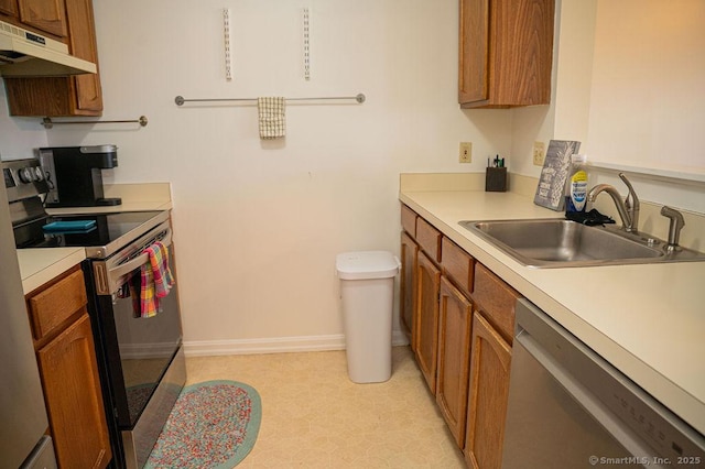 kitchen featuring under cabinet range hood, stainless steel appliances, brown cabinetry, and a sink