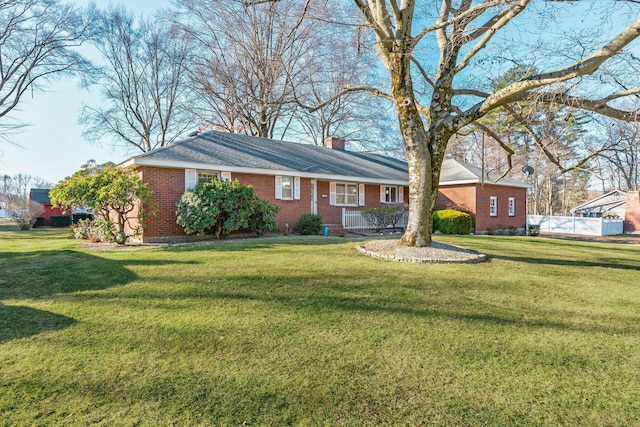 ranch-style home with a front yard, brick siding, a chimney, and fence