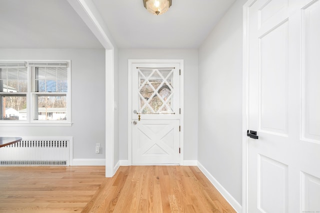 interior space featuring baseboards, light wood-style floors, and radiator heating unit