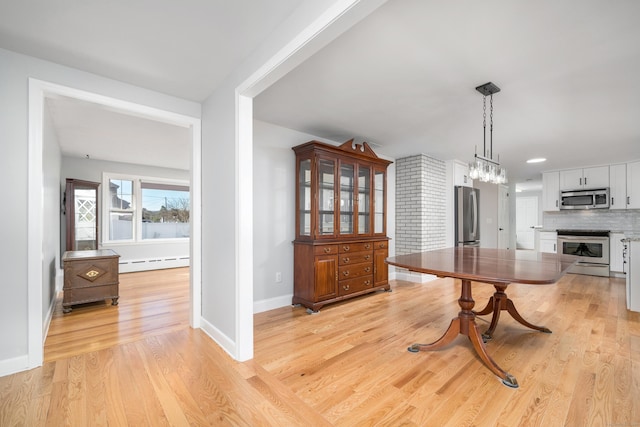 dining space featuring light wood-style flooring, a baseboard heating unit, and baseboards