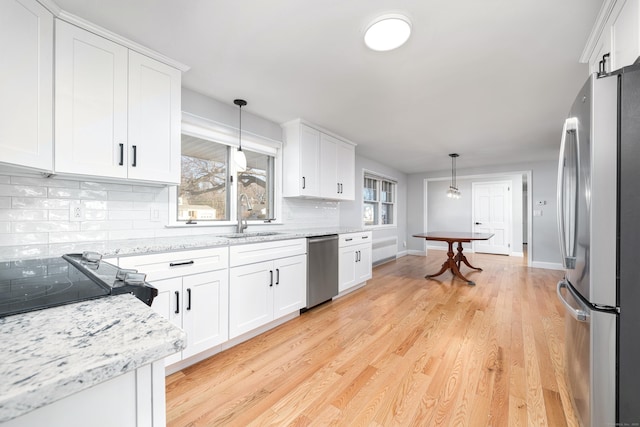 kitchen featuring tasteful backsplash, appliances with stainless steel finishes, light wood-style floors, white cabinets, and a sink