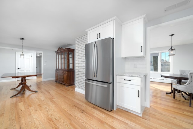 kitchen with visible vents, light wood-style flooring, freestanding refrigerator, white cabinets, and tasteful backsplash