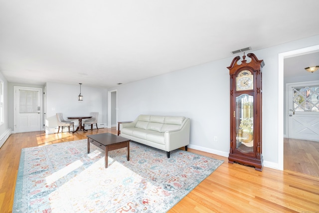 living area with wood finished floors, visible vents, baseboard heating, and baseboards