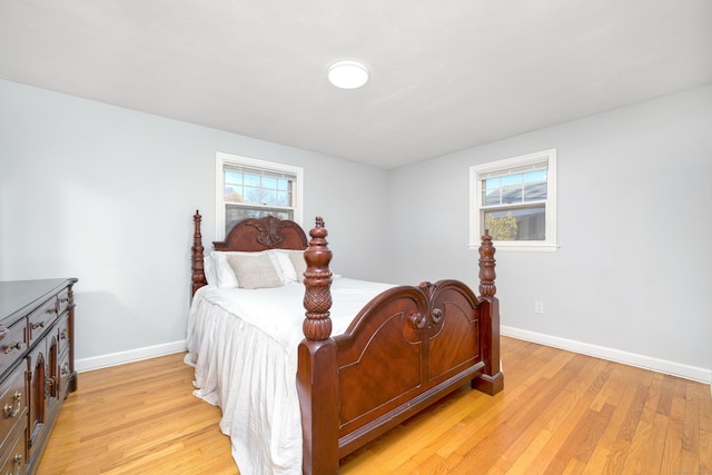 bedroom featuring multiple windows, baseboards, and light wood-style floors