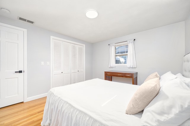 bedroom with visible vents, baseboards, a closet, and light wood finished floors