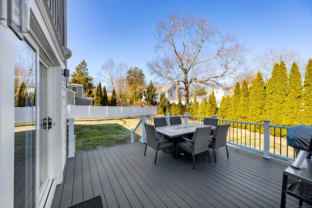 deck with outdoor dining space, a fenced backyard, and a lawn