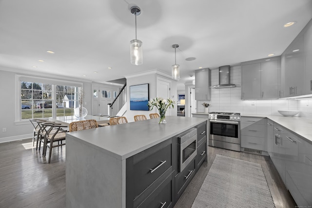 kitchen featuring decorative backsplash, appliances with stainless steel finishes, wall chimney exhaust hood, and gray cabinets