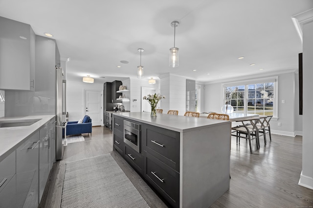 kitchen with dark wood-style floors, a center island, stainless steel appliances, light countertops, and hanging light fixtures