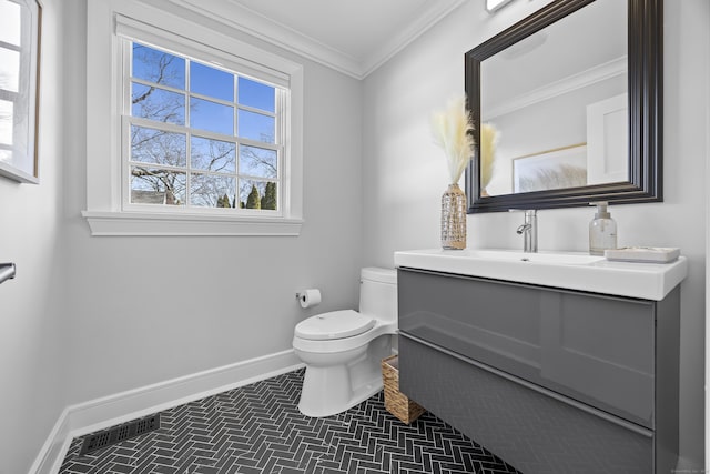 bathroom with vanity, visible vents, baseboards, ornamental molding, and toilet