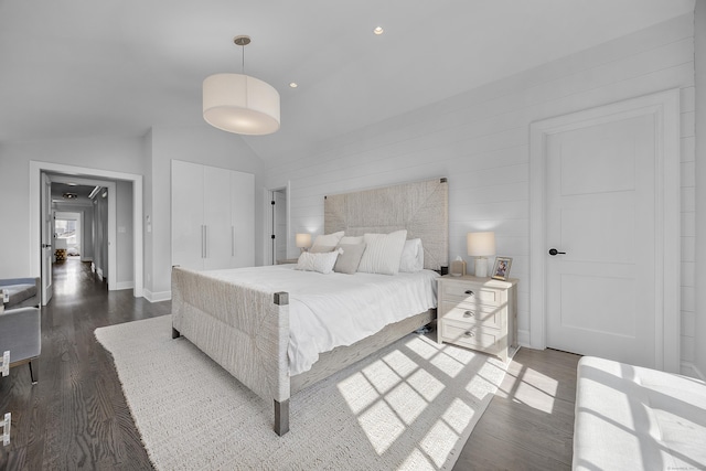 bedroom with a closet, lofted ceiling, baseboards, and wood finished floors