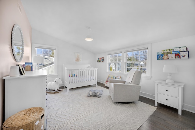 bedroom with wood finished floors, baseboards, visible vents, lofted ceiling, and a crib