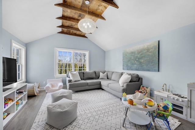 living room with baseboards, wood finished floors, and vaulted ceiling with beams