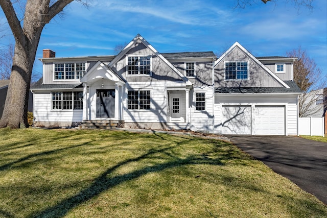 view of front of property with entry steps, a front yard, a chimney, a garage, and driveway