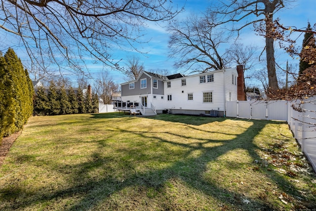 back of house with a lawn, a fenced backyard, a chimney, and a gate