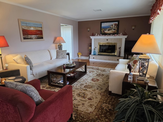 living room featuring visible vents, wood finished floors, a fireplace, and ornamental molding