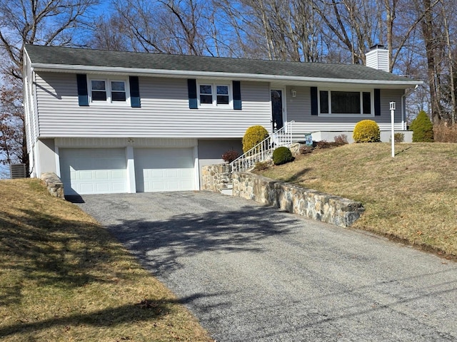 view of front facade with a front yard, roof with shingles, an attached garage, a chimney, and aphalt driveway