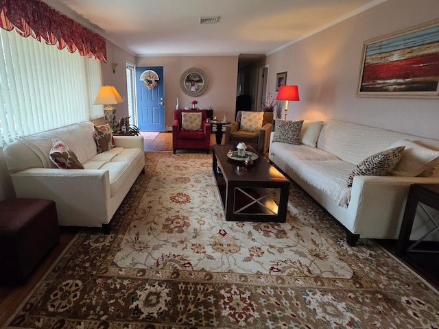 living area featuring visible vents, wood finished floors, and ornamental molding