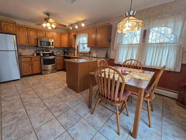 kitchen with brown cabinetry, a peninsula, a sink, appliances with stainless steel finishes, and baseboard heating