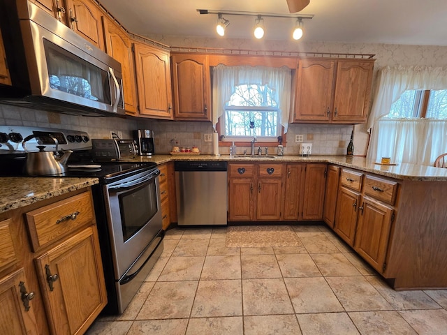 kitchen with brown cabinetry, appliances with stainless steel finishes, and a sink