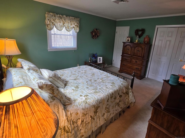 bedroom with visible vents, a closet, ornamental molding, and carpet flooring