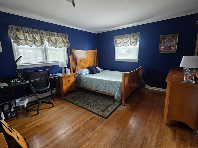 bedroom featuring multiple windows, baseboards, and wood finished floors