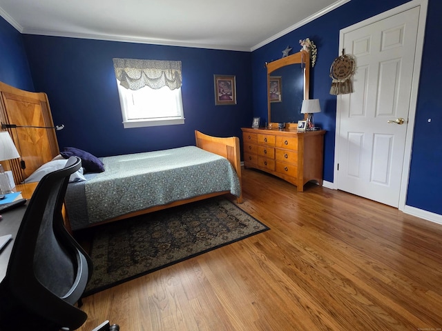 bedroom featuring ornamental molding, baseboards, and wood finished floors