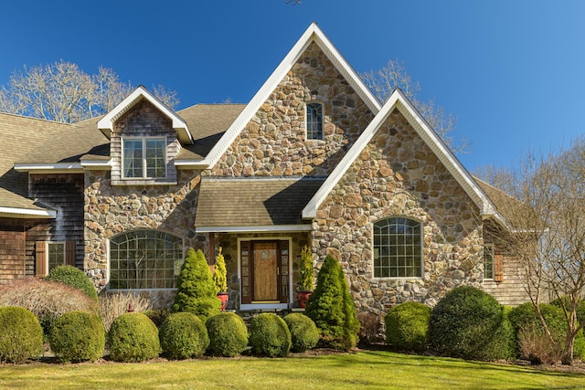 view of front facade featuring a shingled roof and a front yard