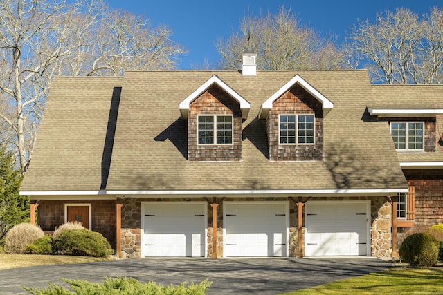 view of front of house featuring aphalt driveway, stone siding, a chimney, and roof with shingles