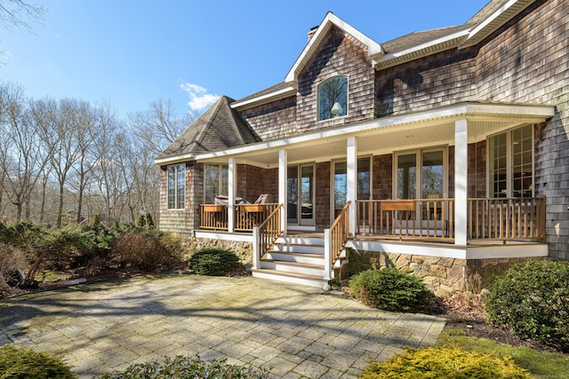 shingle-style home with covered porch and a chimney