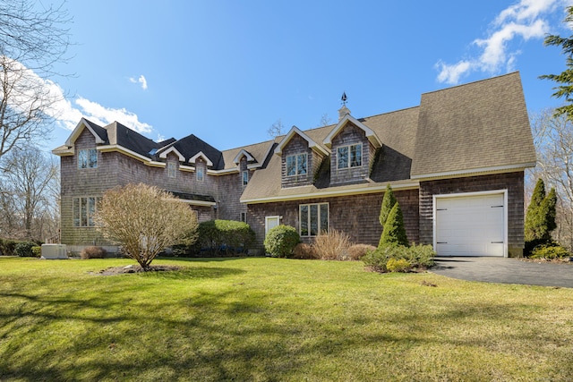 shingle-style home featuring a front lawn, driveway, cooling unit, an attached garage, and a shingled roof