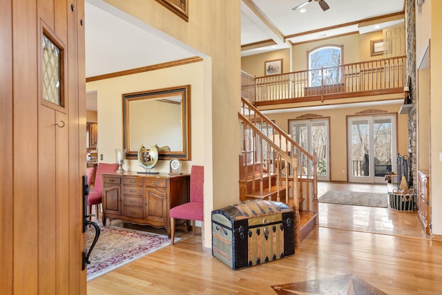 foyer with a healthy amount of sunlight, stairs, a towering ceiling, and wood finished floors