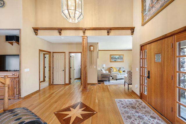 entrance foyer with light wood-style flooring, baseboards, and a towering ceiling