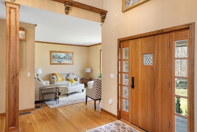 entryway with crown molding, light wood-style flooring, plenty of natural light, and baseboards