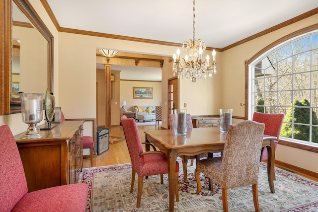 dining area with light wood-type flooring, baseboards, an inviting chandelier, and crown molding