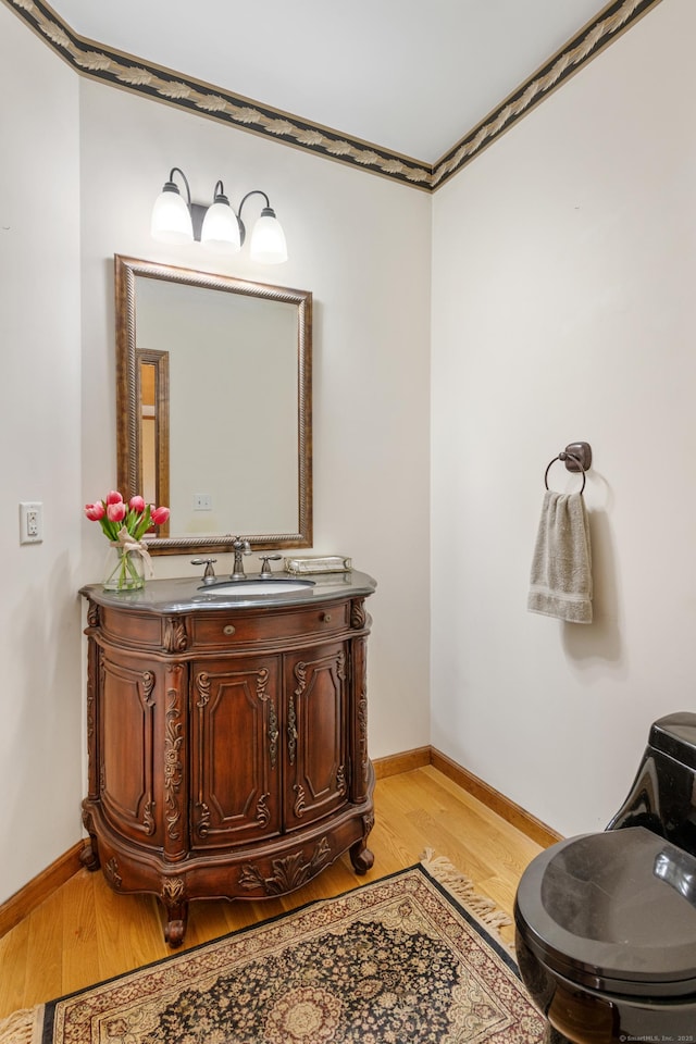 bathroom featuring vanity, wood finished floors, and baseboards