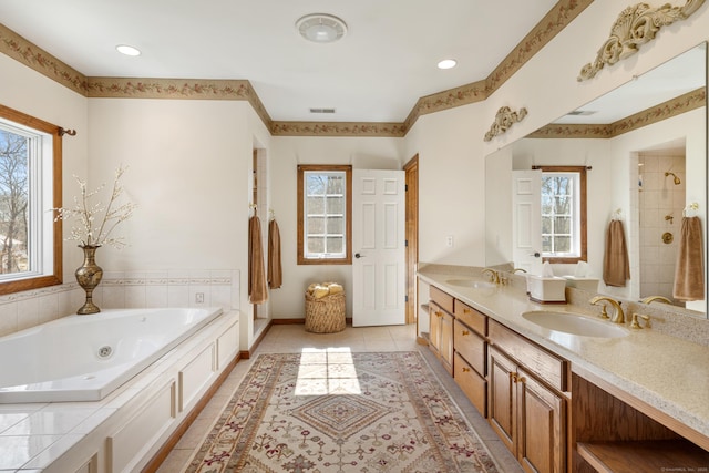 full bath with tile patterned floors, a jetted tub, visible vents, and a sink