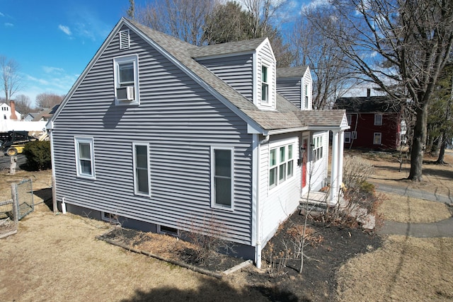 view of side of home featuring cooling unit and a shingled roof